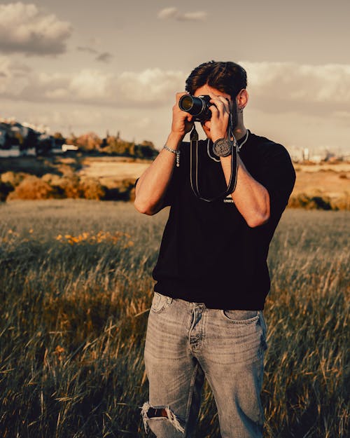 Man in Black T-Shirt Taking Photo on Meadow