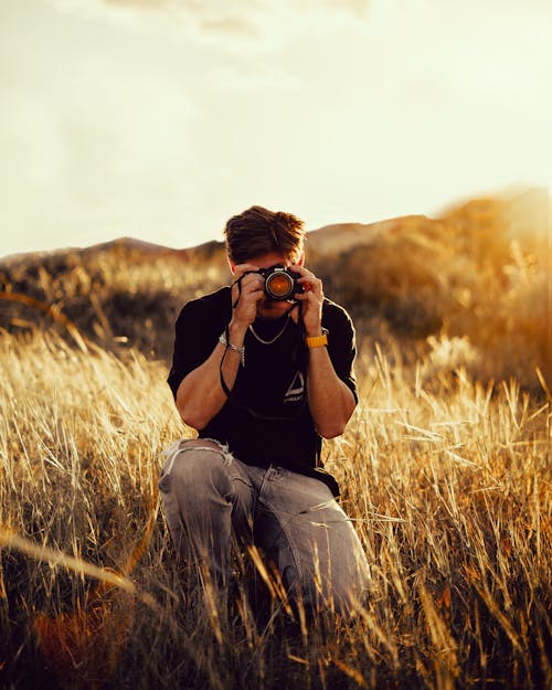 Crouching Man Taking Photo on Field