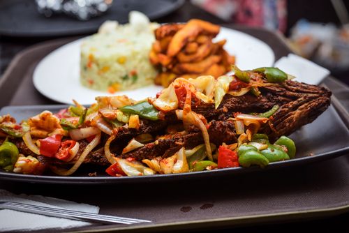 Free Delicious grilled fish topped with vegetables, served with rice and sides for a perfect meal. Stock Photo