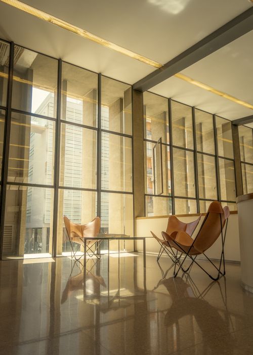 Free Spacious modern lobby featuring large glass windows and minimalist furniture. Stock Photo