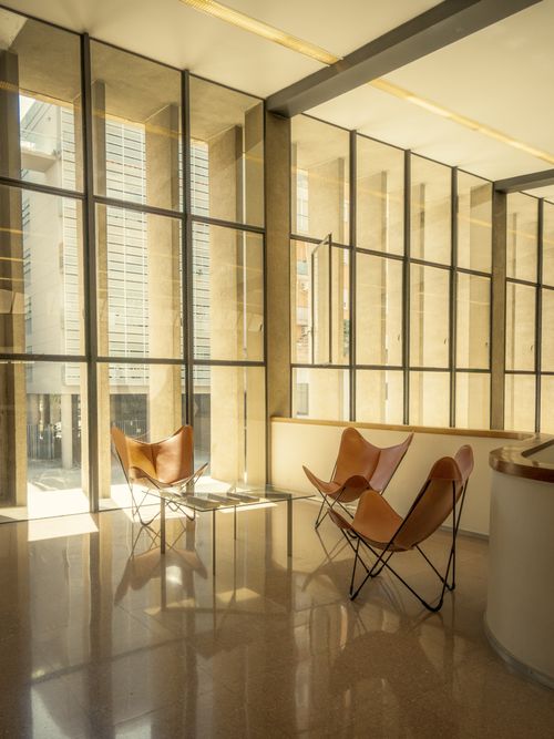 Free Spacious modern interior featuring butterfly chairs, large windows, and soft lighting. Stock Photo
