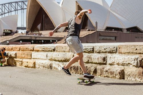 Free A skateboarder executing a trick in front of the Sydney Opera House, capturing urban excitement. Stock Photo