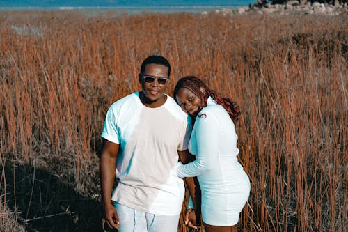 Couple in White Clothes Posing among Grasses