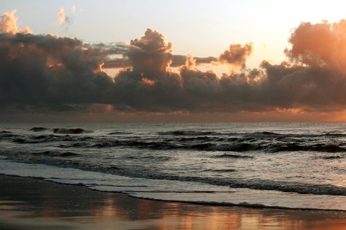 Free Stunning sunset over Guaratuba Beach, Brazil, capturing dramatic clouds and serene waves. Stock Photo