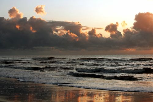 Free Stunning sunset view over the waves at Guaratuba beach, creating a dramatic and vivid seascape. Stock Photo