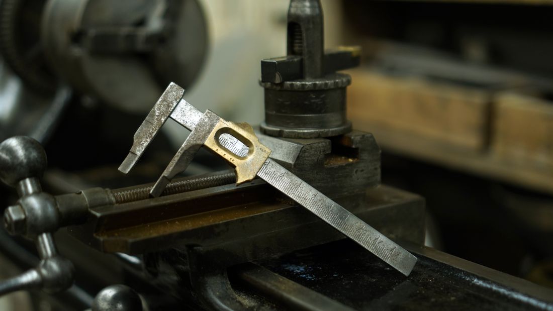 Metal caliper resting on industrial machinery in a workshop