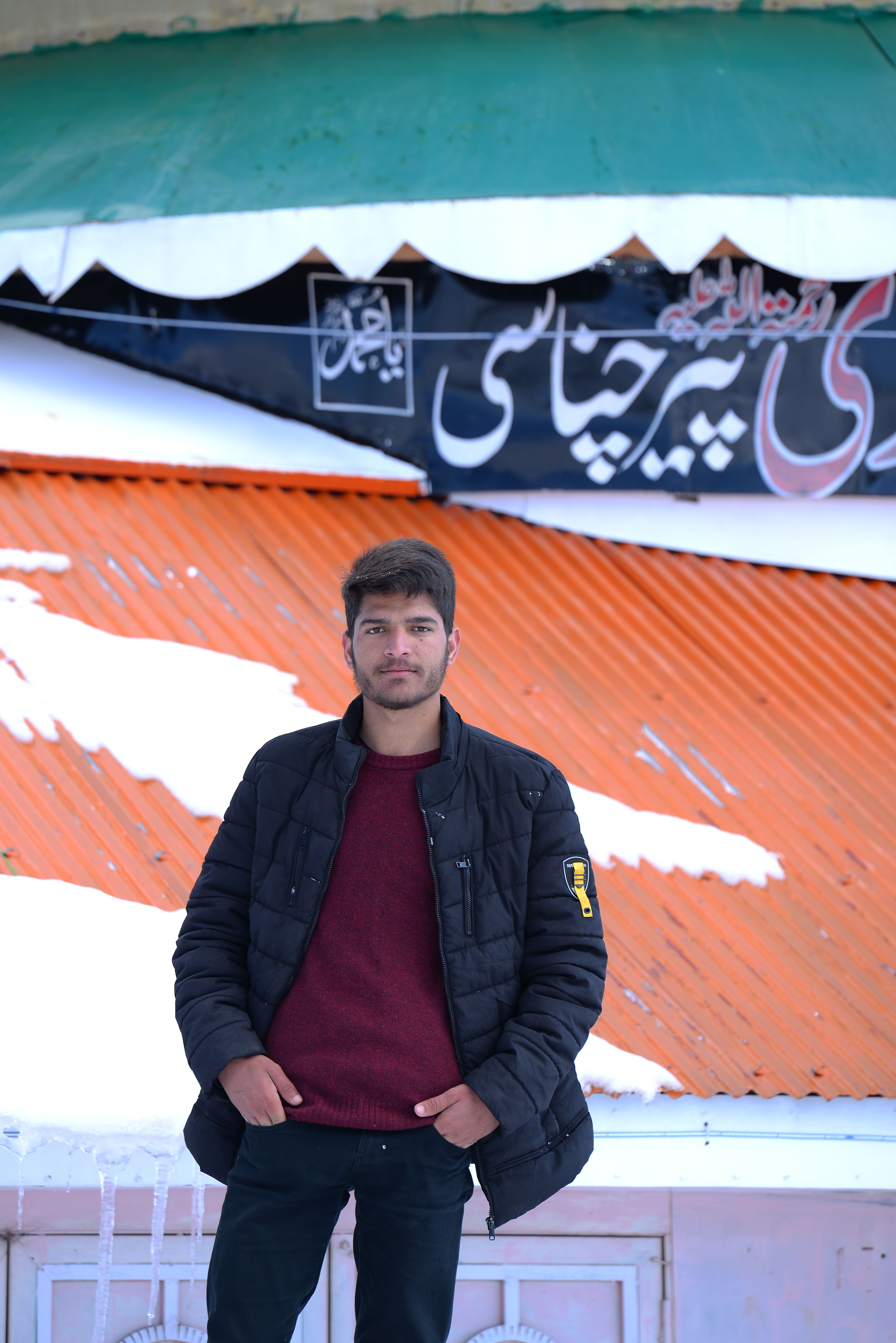 Portrait of a young man posing confidently in a winter setting with a colorful background.