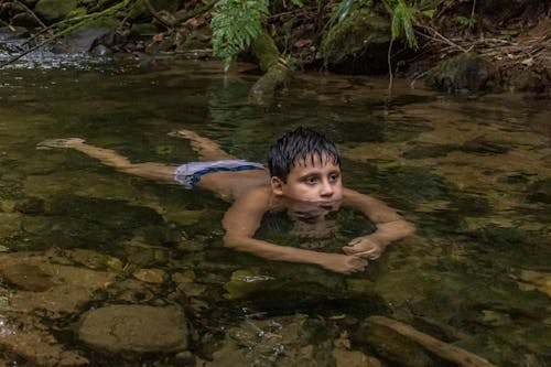 Free Boy Lying Down in Shallow Water Stock Photo