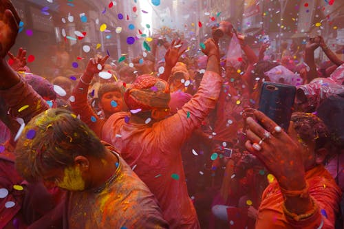 People Celebrating a Traditional Festival with Confetti and Colored Powder 