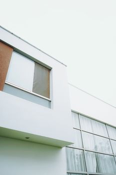 Low angle view of a minimalist white building featuring large windows and sleek lines.