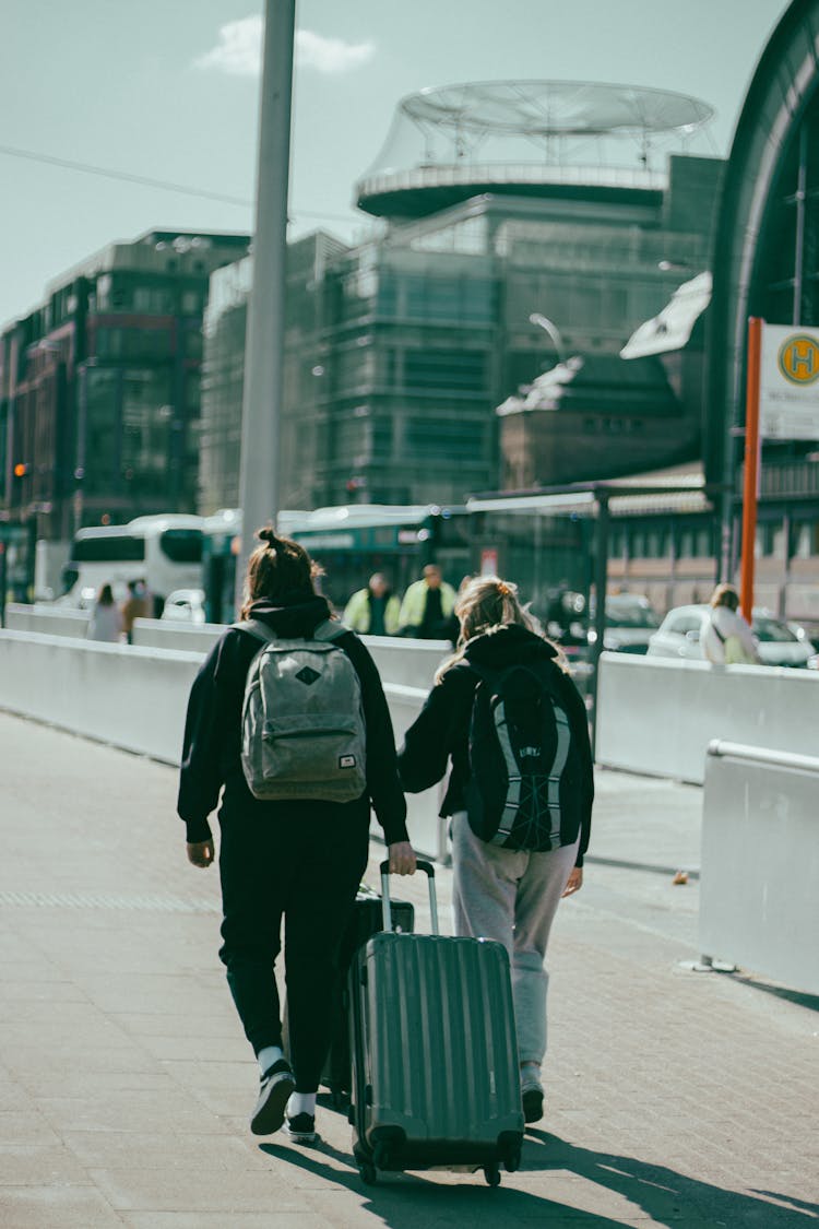 People Walking With Suitcase On Sunlit Sidewalk