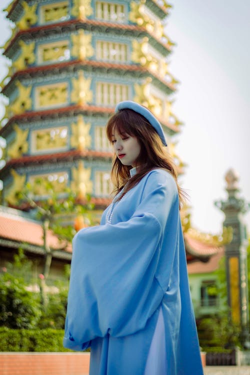 Woman in Blue Robes Posing with Temple behind