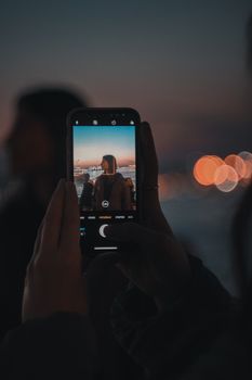A smartphone captures a scenic sunset with bokeh effect in the background.
