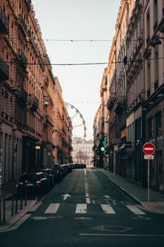 Scenic Lyon city street view featuring a distant Ferris wheel during sunset, rich in architectural style.