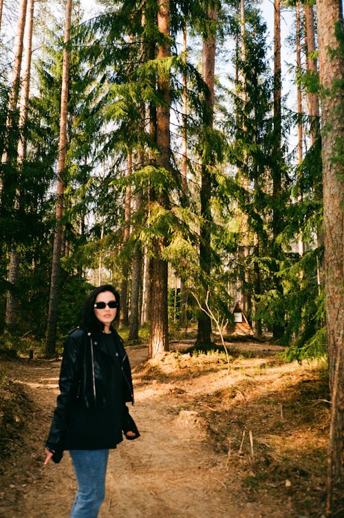 Woman in Black Jacket Posing on Footpath in Forest