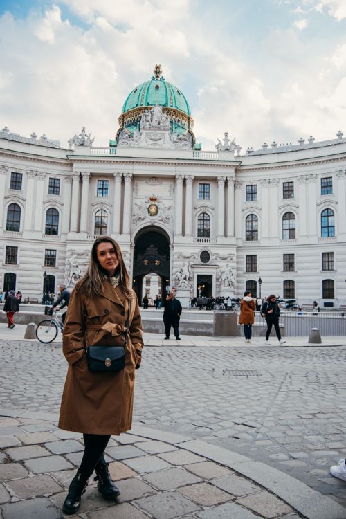 Free Woman in a brown coat posing outside Hofburg Palace in Vienna. Stock Photo