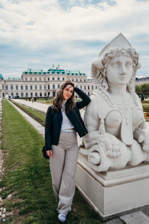 Free A stylish woman poses with a Sphinx sculpture at the historic Belvedere Palace in Vienna, Austria. Stock Photo