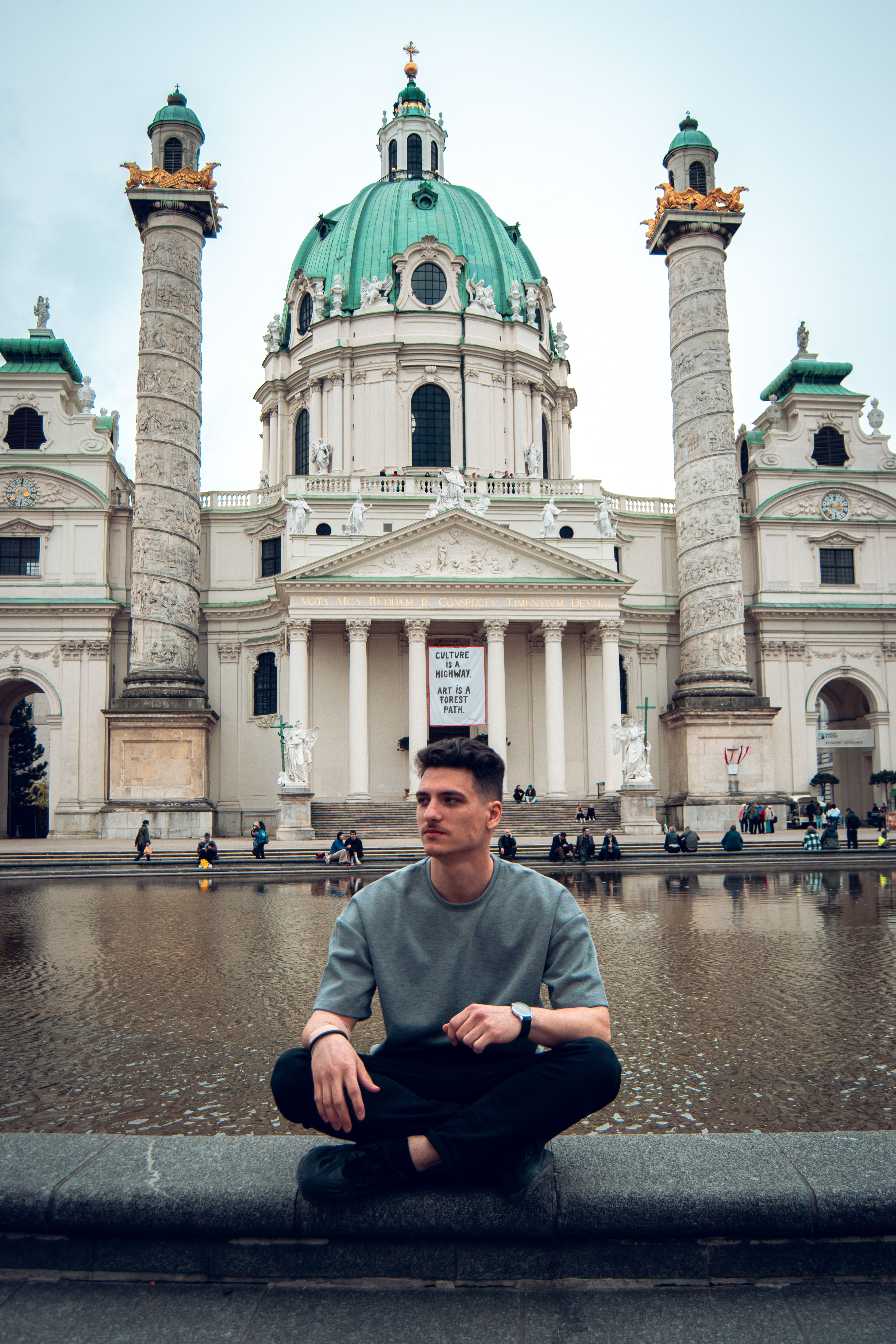 A man poses in front of the iconic St. Charles's Church in Vienna, Austria.