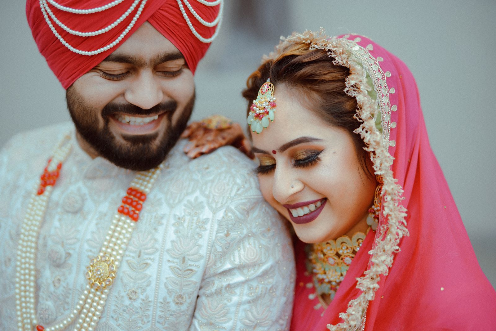 A Sikh couple laughing with their heads tipped together after the Anand Karaj.