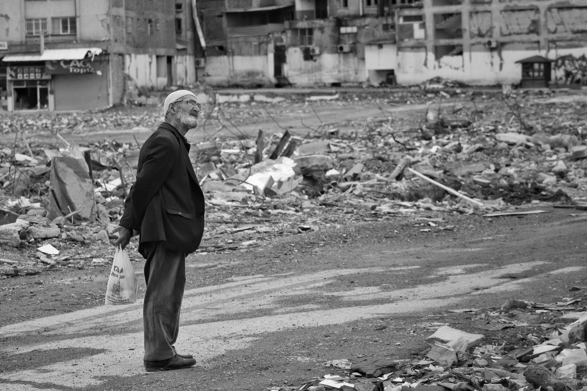 An elderly man stands amidst city ruins, symbolizing resilience after a disaster.