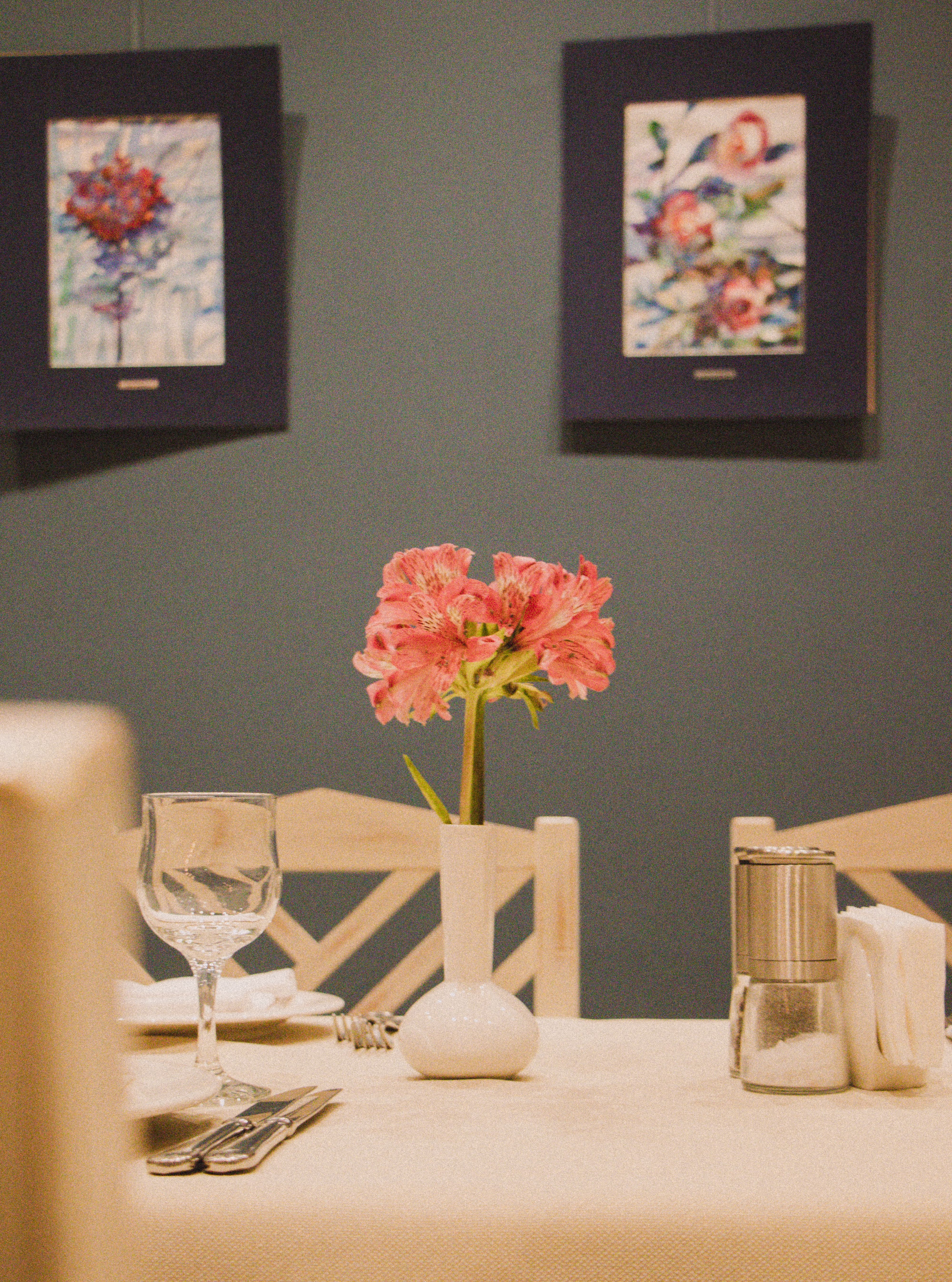 A stylish table setup featuring a vibrant floral centerpiece and elegant dining items against artistic wall decor.