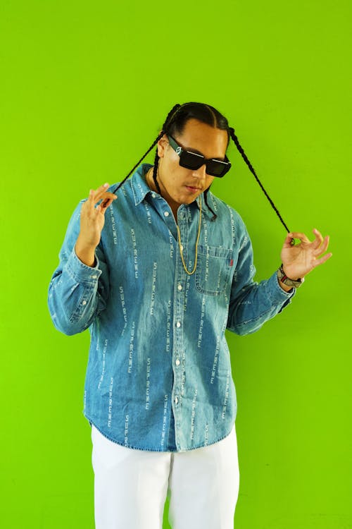 Man in a Blue Shirt Playing with his Braided Hair 