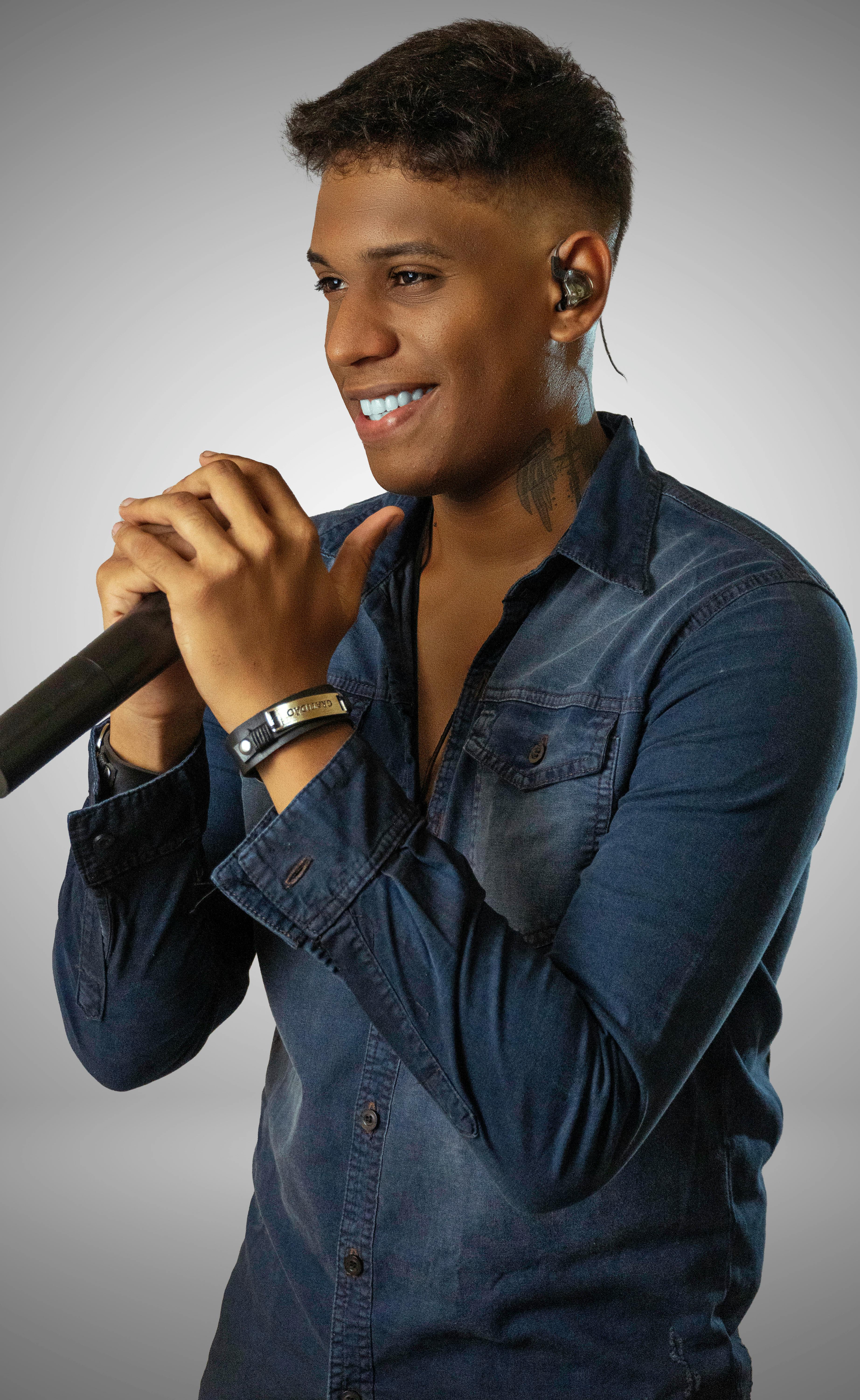 Portrait of a stylish young man posing with a microphone, exuding confidence and charm in a studio setting.