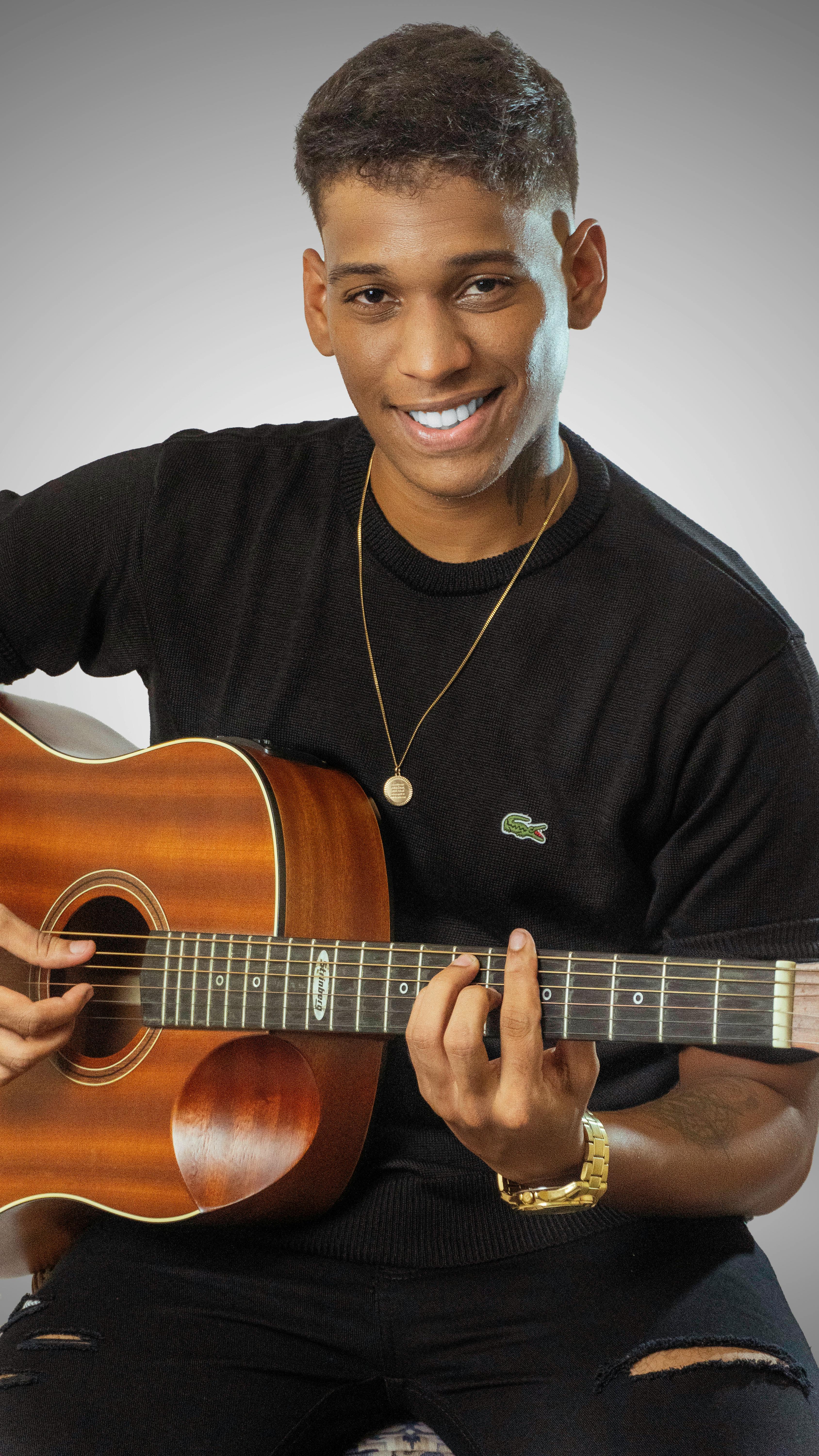 Portrait of a smiling young man playing an acoustic guitar in studio.