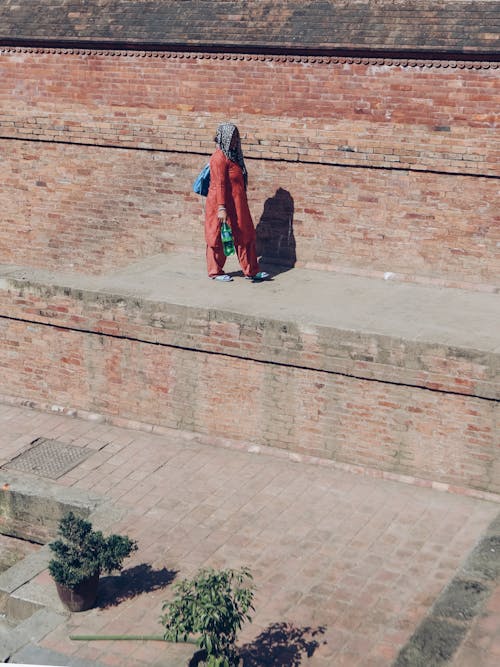 Woman Walking near Sunlit Walls