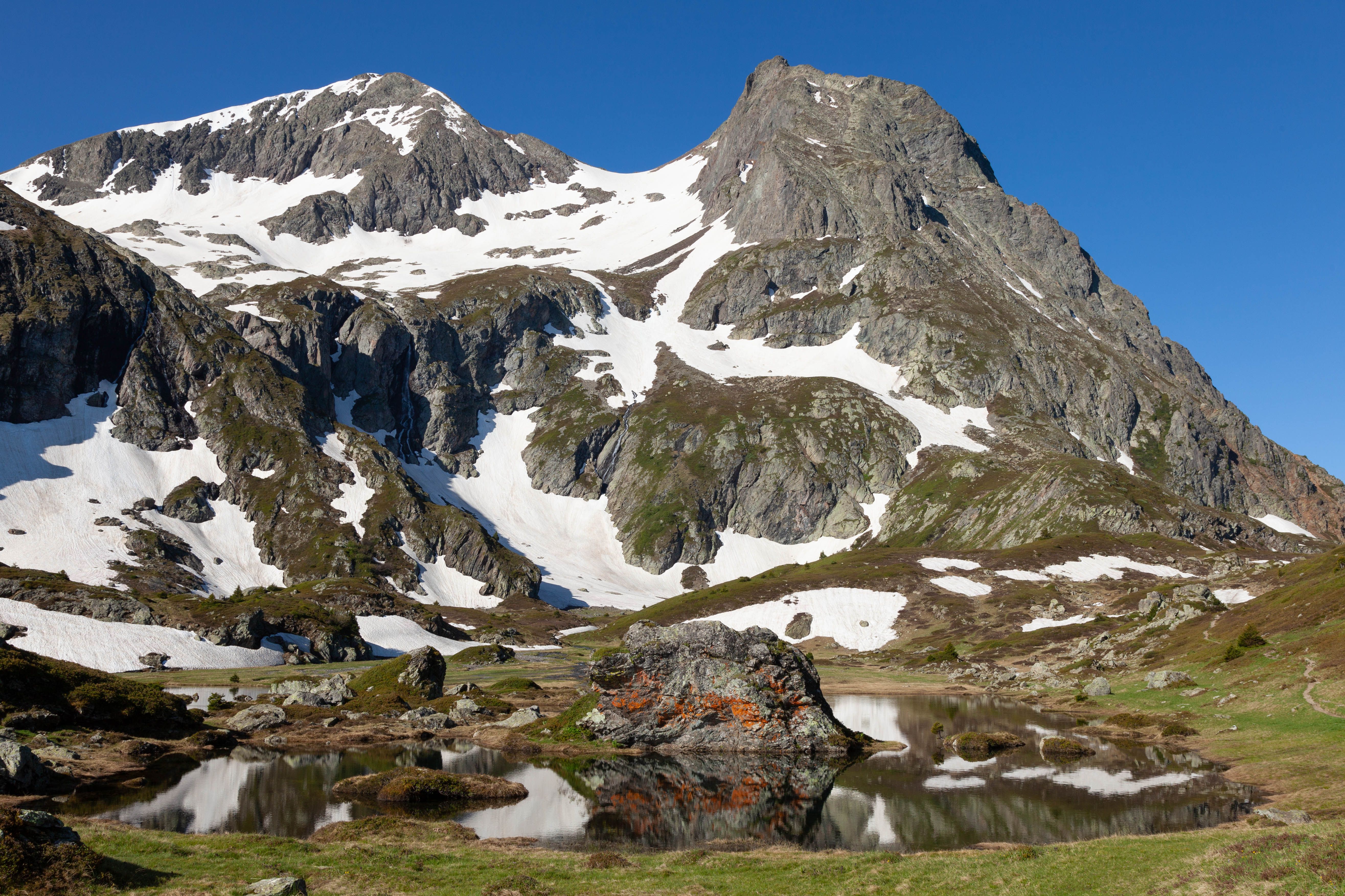 Breathtaking view of snow-capped mountains and a tranquil lake in Le Bourg-d'Oisans, France.