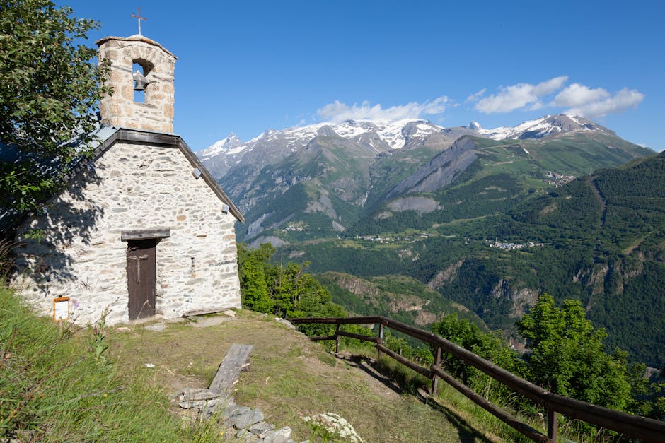 View of a Small Chapel, Green Valley and Snowcapped Mountain Peaks in French Alps