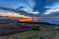 海洋和山丘上的美丽日落，充满活力的天空倒映在水中