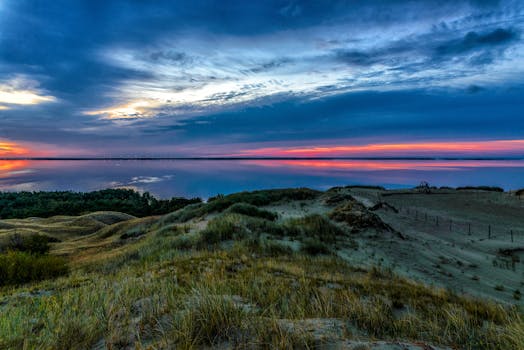 黄昏时分，宁静的沿海景观展现出鲜艳的色彩，平静的海水倒映着日落的色调