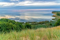 黄昏时分，宁静的湖景中，郁郁葱葱的绿色植物倒映在平静的水面上