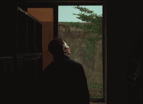 Silhouette of a Man Standing by the Window in a Room 