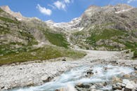 Alpine Landscape with View of a Stream and Mountains under Blue Sky