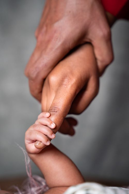 Free A close-up of an adult and baby holding hands, symbolizing connection and care. Stock Photo