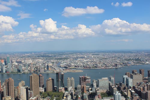 Aerial View of City Buildings by River Under Blue Cloudy Skies