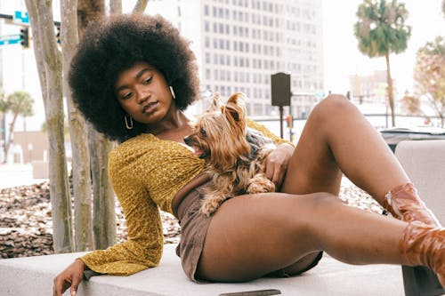 Young Woman in a Fashionable Summer Outfit Lying Outside with Her Little Dog