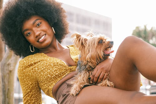 Young Woman in a Fashionable Summer Outfit Lying with Her Little Dog and Smiling 