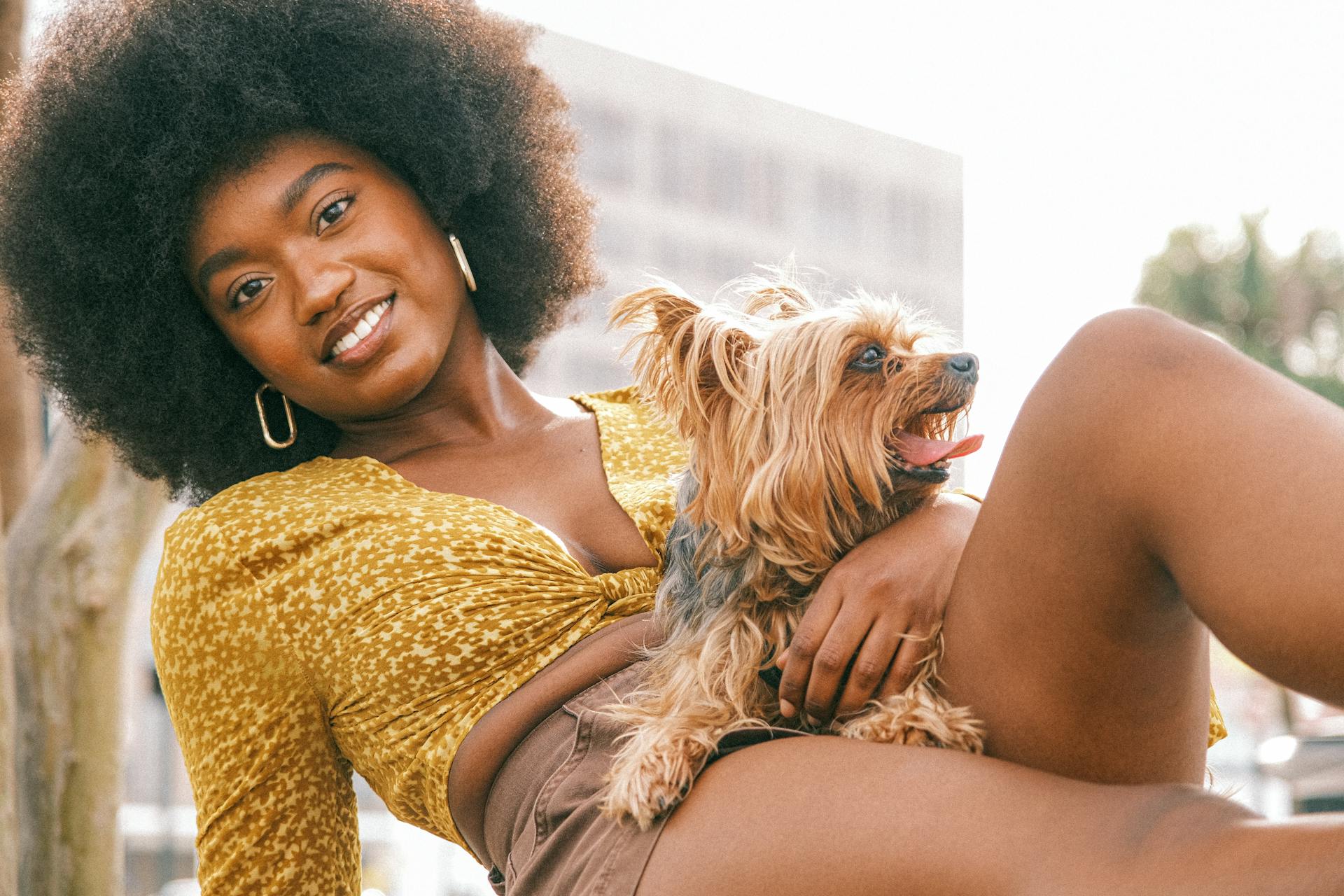 Young Woman in a Fashionable Summer Outfit Lying with Her Little Dog and Smiling