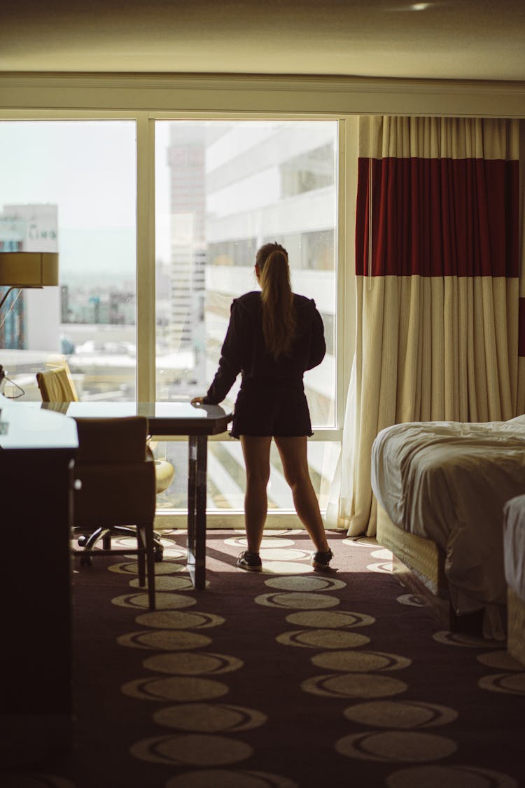 Woman By Window In Hotel Room