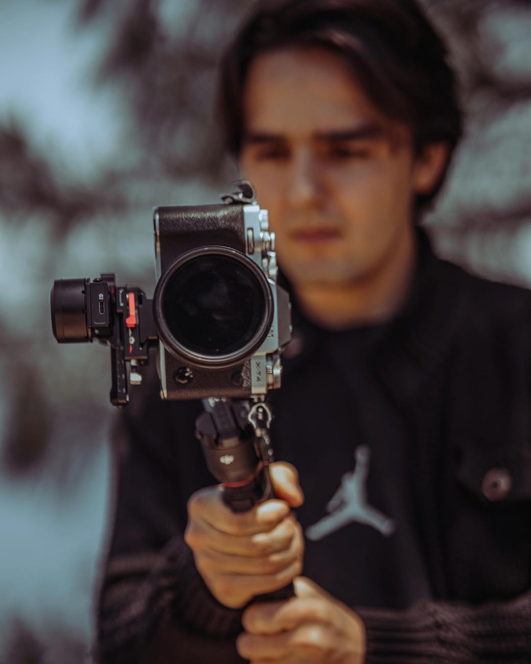 Blurred background focus on camera stabilizer held by a man outdoors.