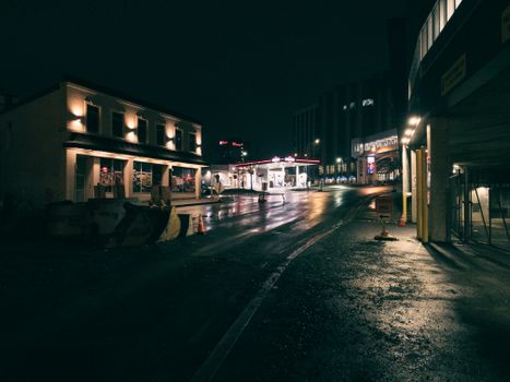 Moody urban street at night in St. John's, NL, with illuminated buildings and wet pavement.