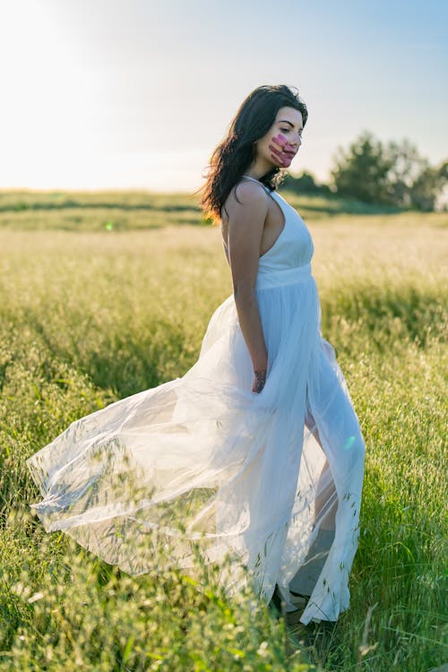 Model with Symbol on Face in White Dress Posing in Meadow