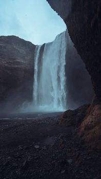 Dramatic waterfall cascading through rocky canyon, creating misty ambiance.