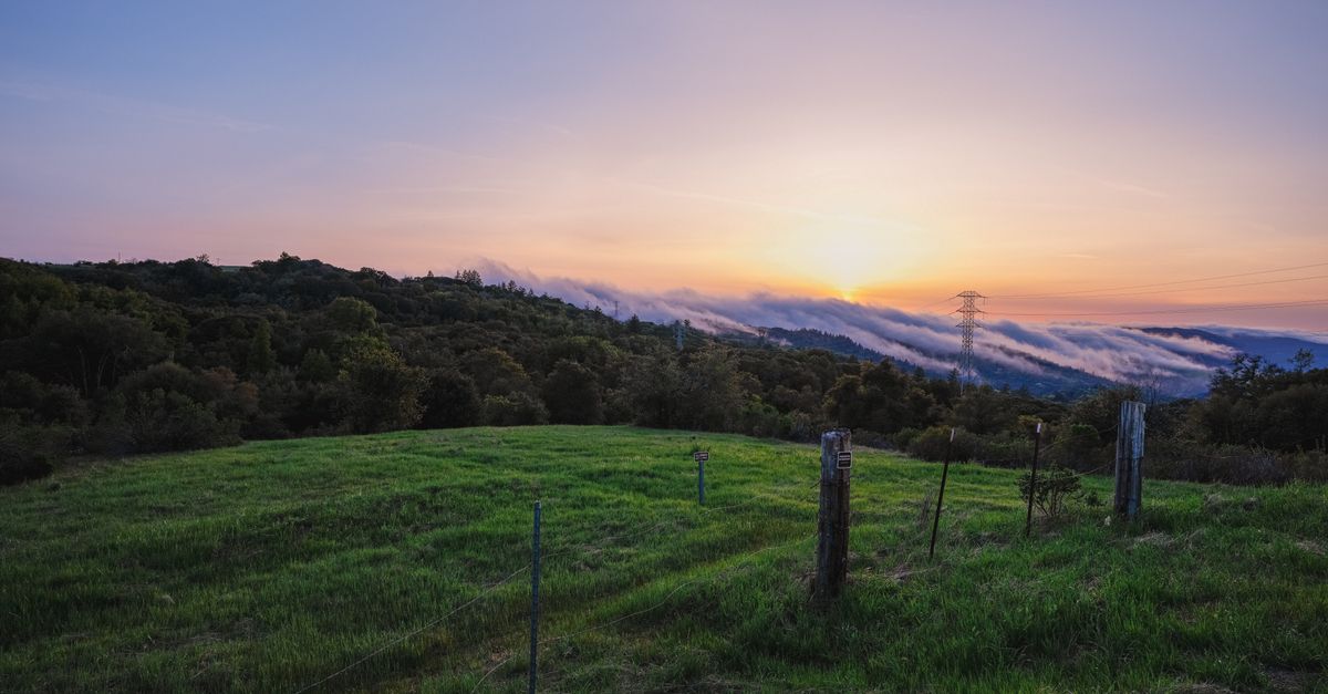 Breathtaking sunset over green hills and distant clouds in Palo Alto, CA. Perfect for landscape lovers.