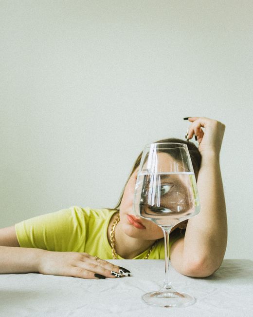 A creative portrait capturing water refraction through a wine glass, enhancing artistic ambiance.