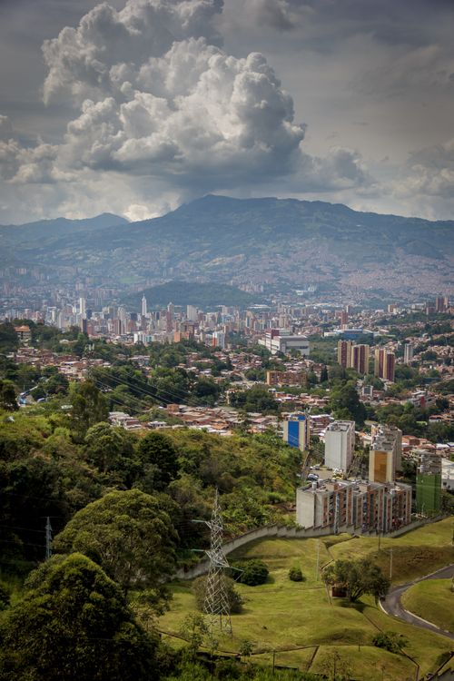 Free Stunning aerial view of Medellin cityscape under dramatic clouds and lush mountain backdrop. Stock Photo