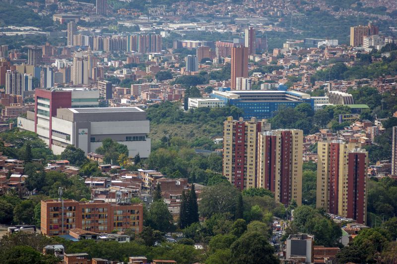 Aerial view of a bustling urban cityscape with tall buildings surrounded by greenery.